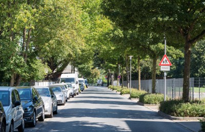 Uhlandstraße mit parkenden Autos links und Hinweisschild auf spielende Kinder