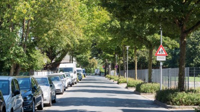 Uhlandstraße mit parkenden Autos links und Hinweisschild auf spielende Kinder