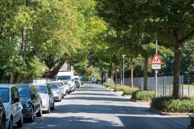 Uhlandstraße mit parkenden Autos links und Hinweisschild auf spielende Kinder