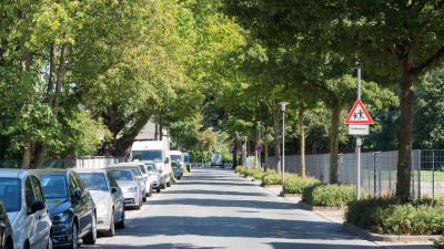 Uhlandstraße mit parkenden Autos links und Hinweisschild auf spielende Kinder