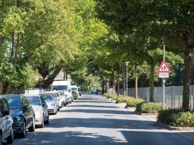 Uhlandstraße mit parkenden Autos links und Hinweisschild auf spielende Kinder